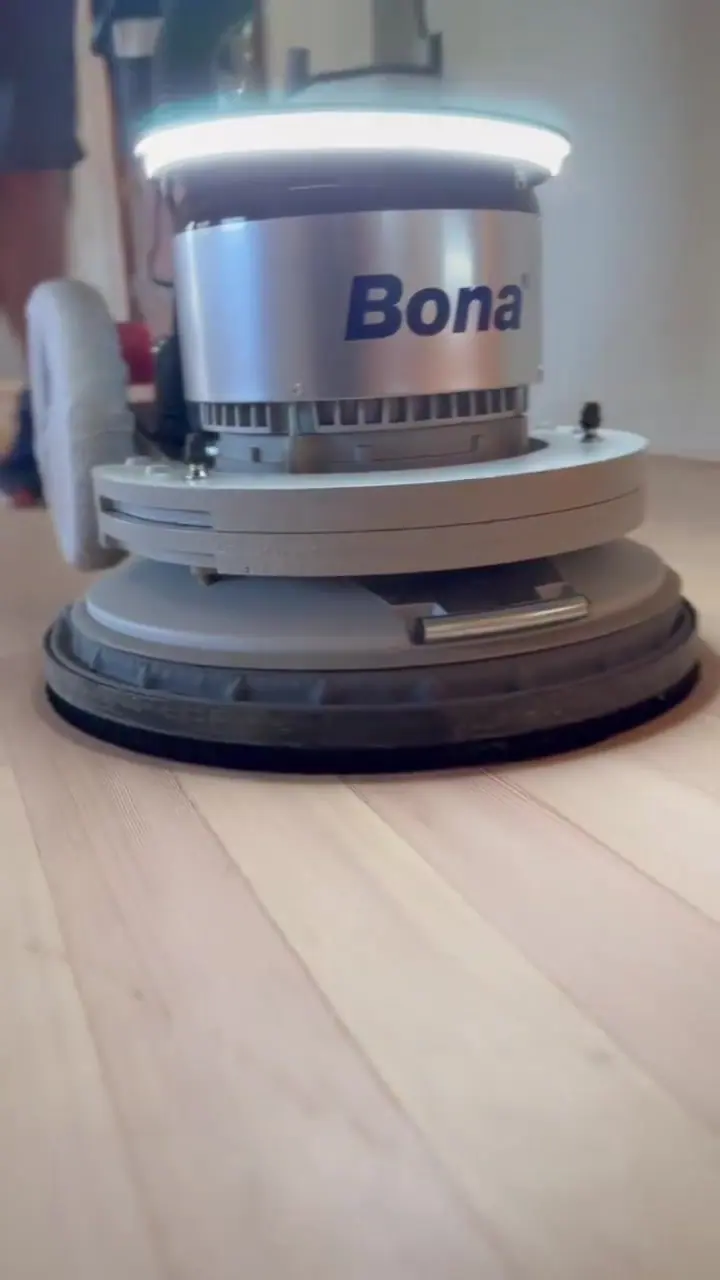 Close-up of a sander head on a hardwood floor.