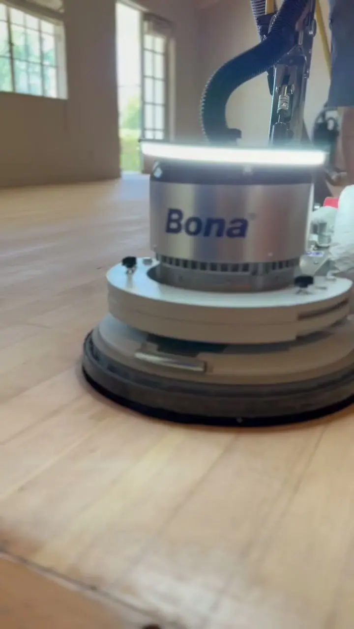 Close-up of a floor sander on a hardwood floor.